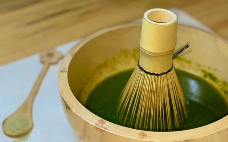 Fine powdered genmaicha and hojicha tea in ceramic bowls with a bamboo whisk.