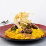 A glass of Brunello di Montalcino wine paired with porcini mushroom risotto on a rustic table.