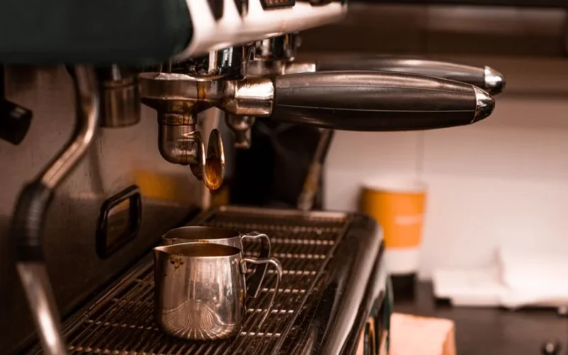 Close up of fresh espresso being poured into a white ceramic cup at a coffee festival.
