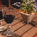 Overhead view of amber fortified wine and red Cabernet Sauvignon on a dark wooden surface.