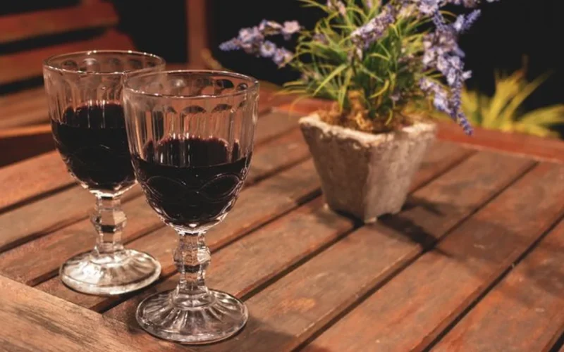 Overhead view of amber fortified wine and red Cabernet Sauvignon on a dark wooden surface.