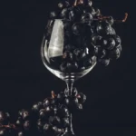 Overhead view of fresh purple grapes and wine glasses on a rustic wooden table.
