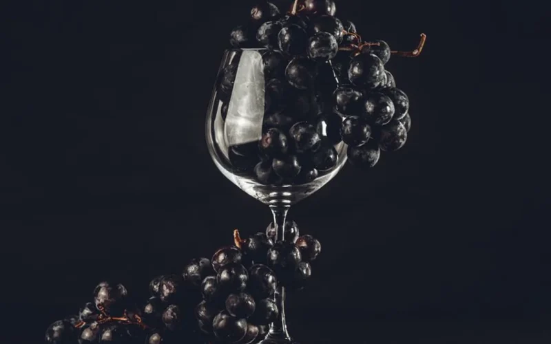 Overhead view of fresh purple grapes and wine glasses on a rustic wooden table.