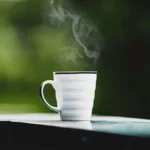 Close-up of a person holding a steaming hot mug of coffee or tea.