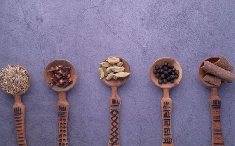Traditional Somali spiced coffee with cardamom and cinnamon pods on a wooden table.