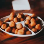 A glass of sparkling champagne paired with crispy chicken nuggets on a wooden surface.