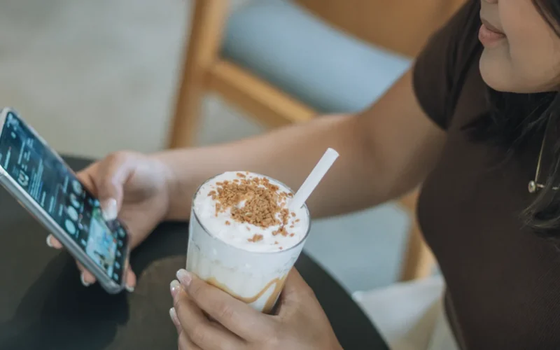 Person using a mobile app to order an iced specialty coffee drink