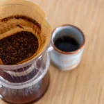 Close up of specialty coffee being poured into a reusable ceramic mug at a festival.