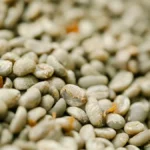 Raw green Arabica coffee beans spilling from a burlap sack on a wooden table.