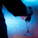 A red wine glass and headphones on a dark table in a dimly lit lounge.