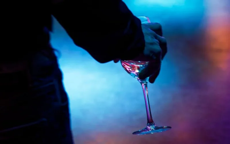 A red wine glass and headphones on a dark table in a dimly lit lounge.