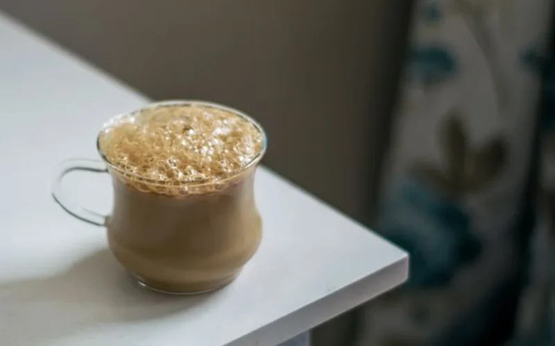 A steaming cup of traditional Yemeni spiced coffee with cardamom and cinnamon on a dark counter.