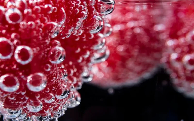 Close-up macro view of fine bubbles rising in a pale red sparkling wine.