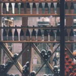 Overhead view of wine bottles and business invoices on a wooden surface.