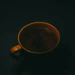 Blue Bottle coffee bag and ceramic cup on a dark stone surface with dried fruit.