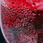 Close-up detail of a crystal wine glass with condensation on a wooden surface.
