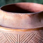 Close-up texture of a porous clay amphora vessel used for wine fermentation.