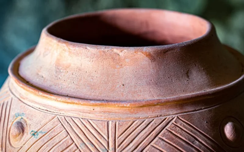 Close-up texture of a porous clay amphora vessel used for wine fermentation.