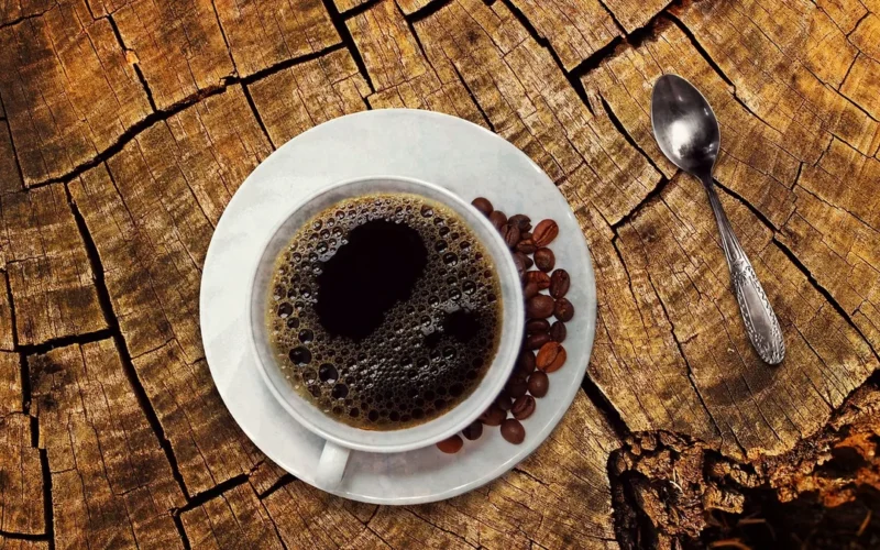 A digital tablet showing a map next to green coffee beans on a wooden surface.