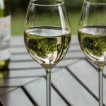 A bottle of Alquimia Vin de Voile and a glass on a stone ledge.