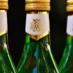 A bottle of Tio Pepe Fino En Rama Sherry next to a glass on a wooden bar.