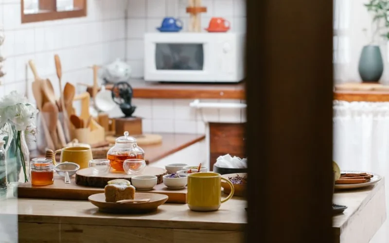 A ceramic teapot and cups resting on a stone surface with dried green tea leaves.