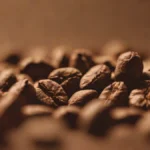 Lightly roasted coffee beans resting on a wooden surface next to a burlap sack.