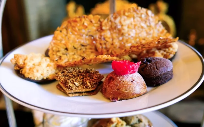 Overhead view of seasonal Halloween themed afternoon tea pastries and sweets on a dark table.