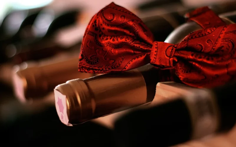 A bottle of red wine and a glass on a dark wooden table.