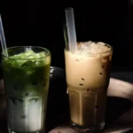 A bowl of green matcha and a cup of spiced chai on a marble surface.