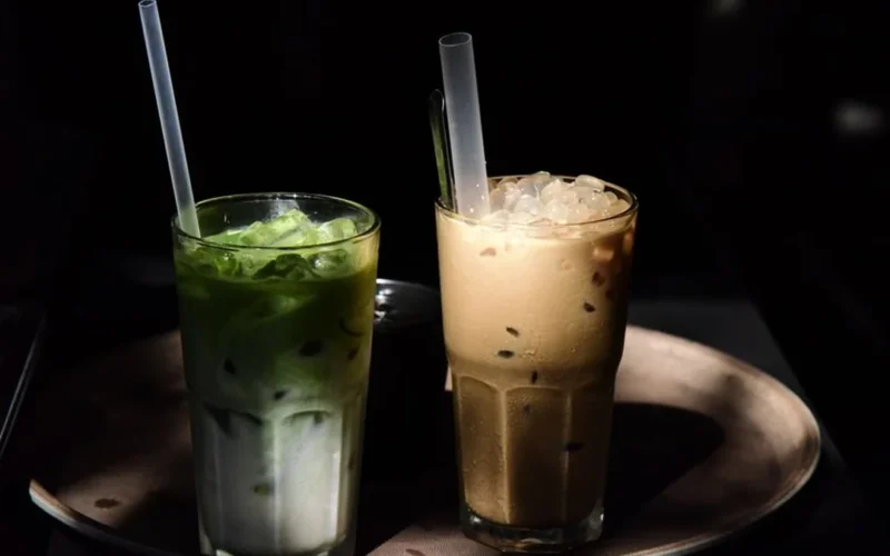 A bowl of green matcha and a cup of spiced chai on a marble surface.