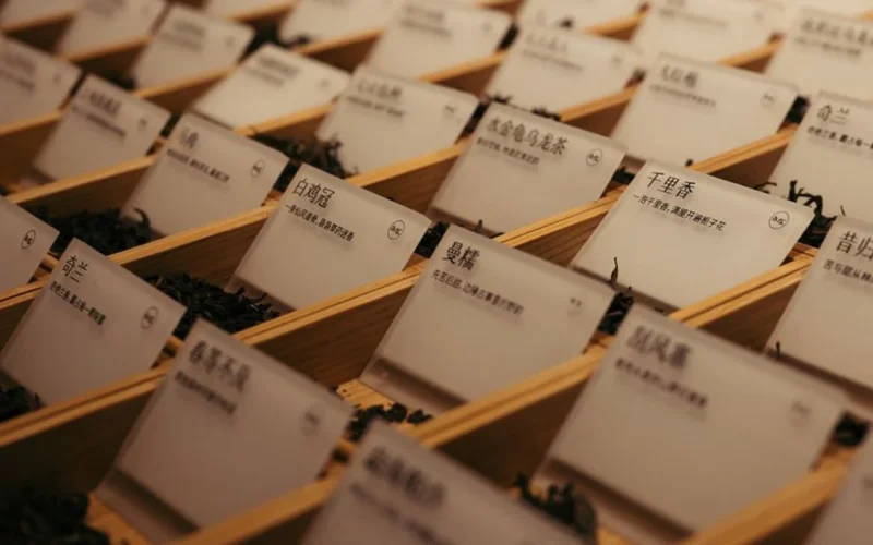Assorted loose leaf tea varieties including dark pu'er and green oolong on a stone surface.