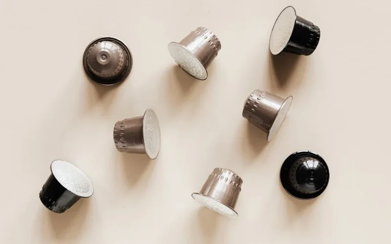 Aluminum and paper coffee capsules resting on a dark stone countertop surface.