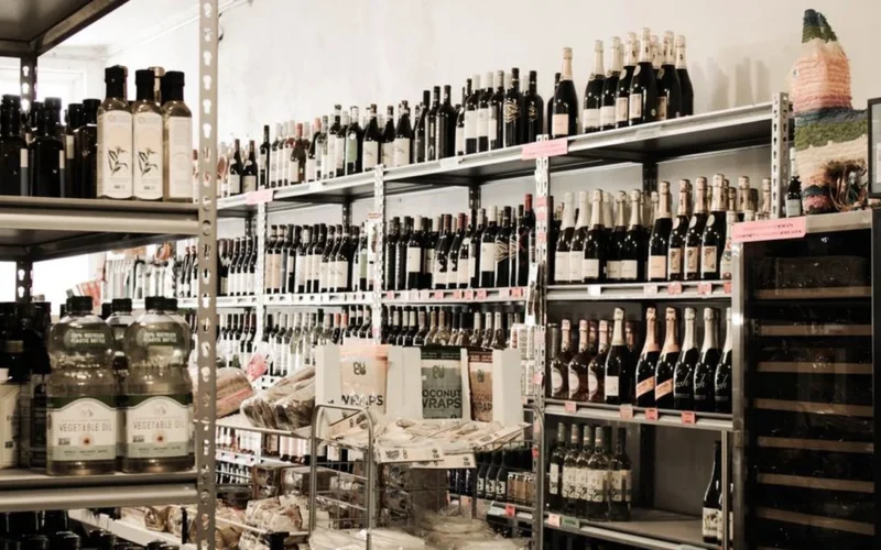 Rows of various wine bottles displayed on organized supermarket shelves in a grocery store.