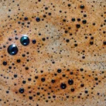 Close-up macro shot of rich golden espresso crema in a white ceramic cup.