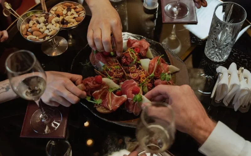 Red wine glasses and gourmet appetizers on a rustic wooden dining table.