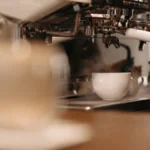 A ceramic coffee cup resting on a white quartz bar near books and dark blue walls.