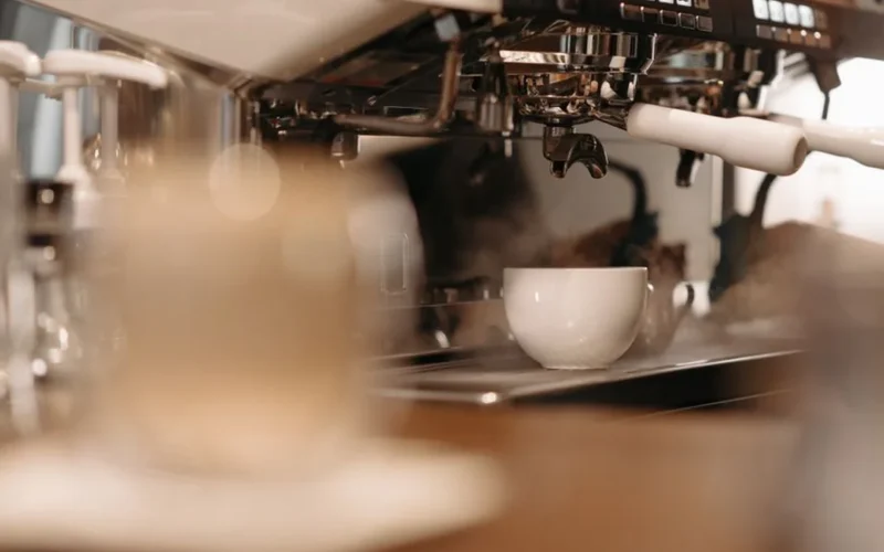 A ceramic coffee cup resting on a white quartz bar near books and dark blue walls.