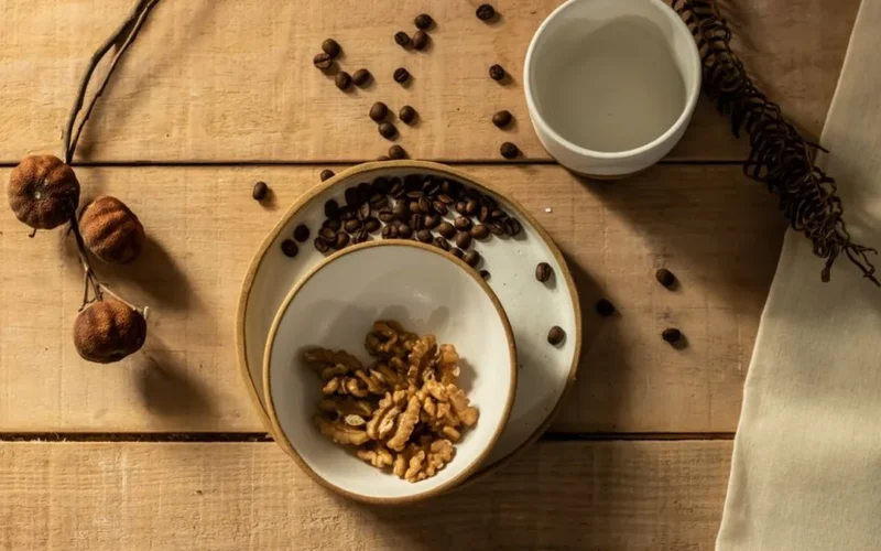 Overhead view of black coffee in a ceramic bowl surrounded by dried mushrooms and beans.