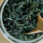 Close-up texture of dried Darjeeling black tea leaves with golden tips on slate.