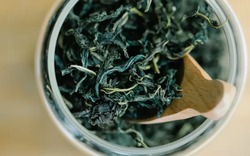 Close-up texture of dried Darjeeling black tea leaves with golden tips on slate.