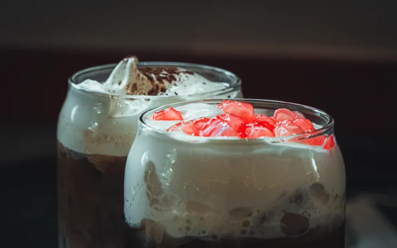 Close-up of swirling milk and espresso in a glass of iced specialty coffee.