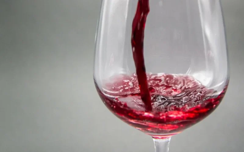 Close-up macro shot of swirling deep red wine showing light and texture.