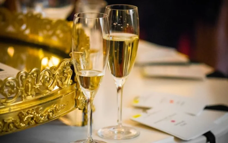 Overhead view of white wine bottles, glasses, and gold award medals on a wooden surface.