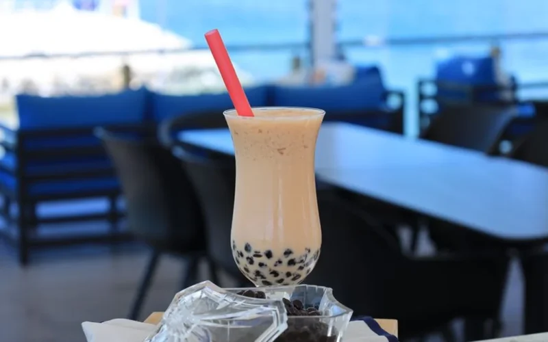 A pink kitten miniature teapot emitting dry ice smoke next to a boba milk tea.