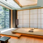 An elegant bamboo tea room interior featuring a matcha dessert on a stone table.