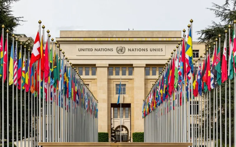 Wide shot of an empty international diplomatic assembly hall with rows of desks and microphones.
