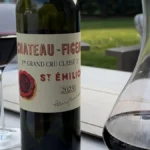 A bottle of red wine and a glass on a wooden table in a cellar.