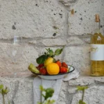 A bottle of Furmint wine resting on volcanic stone next to an oak barrel.