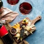 Overhead view of red wine and a mushroom provolone cheesesteak on a rustic table.